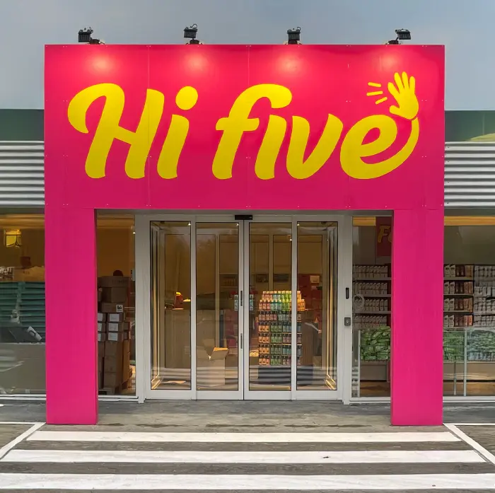 Indgang til Hi Five butik med pink facade og gul logo, der signalerer energi, overraskelser og lave priser.